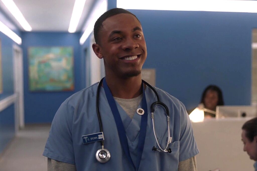 Gino Brown wearing blue scrubs smiling